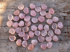 Several small rose quartz crystal hearts 30mm on wood table