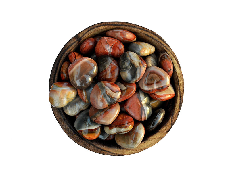 Several polychrome jasper crystal hearts 30mm inside a wood bowl on white background