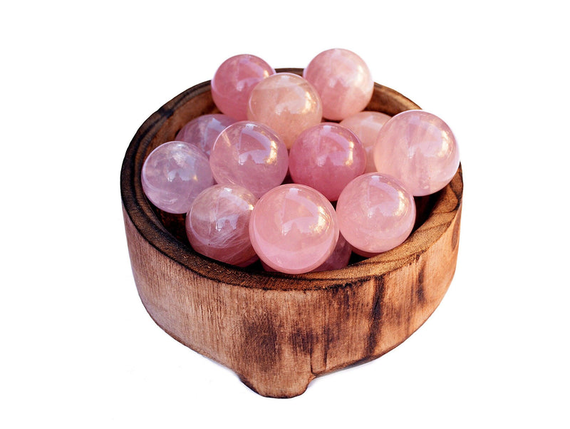 Several pink quartz sphere crystals 25mm-40mm inside a wood bowl on white background