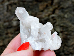 One small rough quartz crystal cluster on hand with gray background