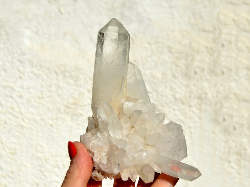 One big quartz crystal cluster on hand with white background
