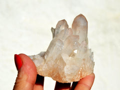 Rough crystal quartz cluster on hand with white background