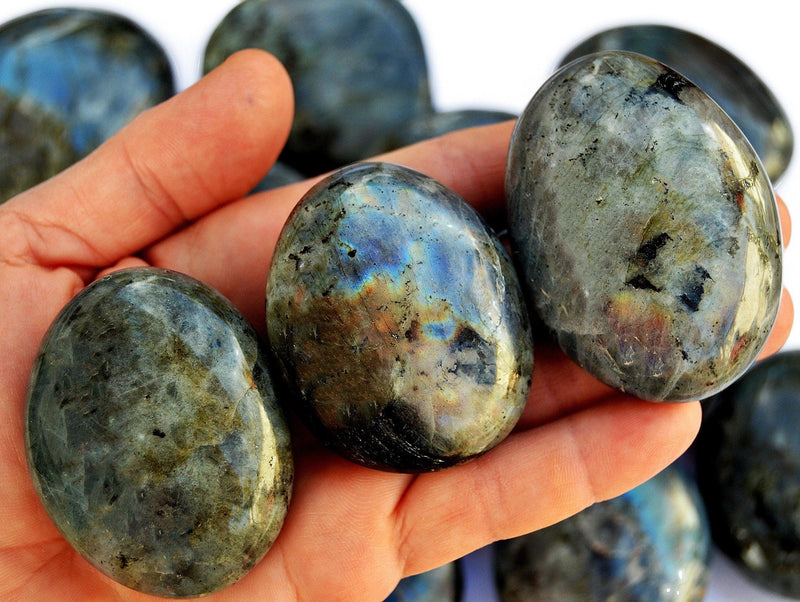 Three labradorite palm stones different sizes with background with some stones