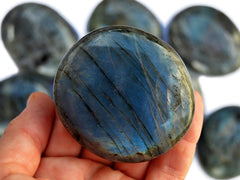 One flash blue labradorite 75mm on hand with background with some crystals