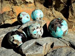 Five large green amazonite crystal spheres 65mm - 100mm on natural rock
