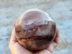 One large fire quartz minerals sphere 90mm on hand with wood background