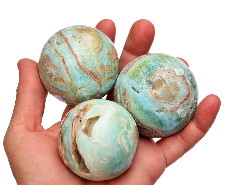Three blue aragonite spheres 55mm-60mm on hand with white background