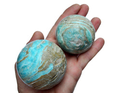 Two blue aragonite crystal balls 55mm-70mm on hand with white background