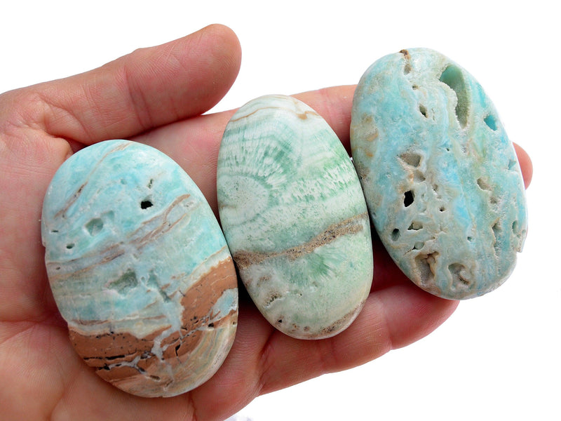 Three blue green aragonite palm stones 50mm-60mm on hand with white background
