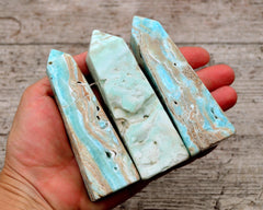 Three blue aragonite faceted points on hand with wood background
