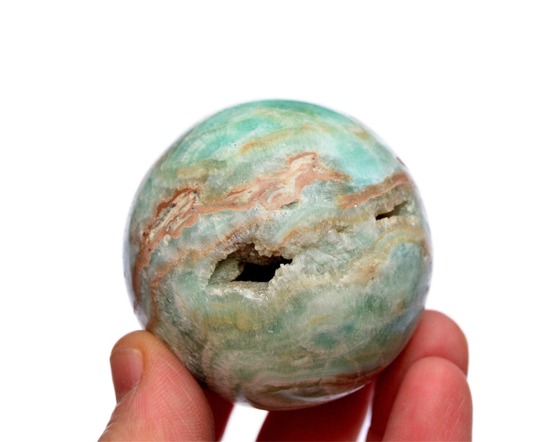 One druzy blue green aragonite crystal sphere 55mm on hand with white background