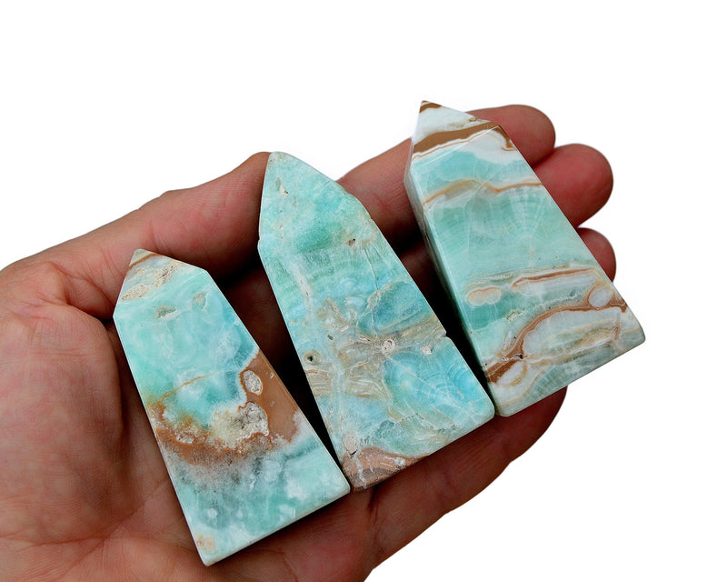 Three small blue aragonite towers on hand with white background