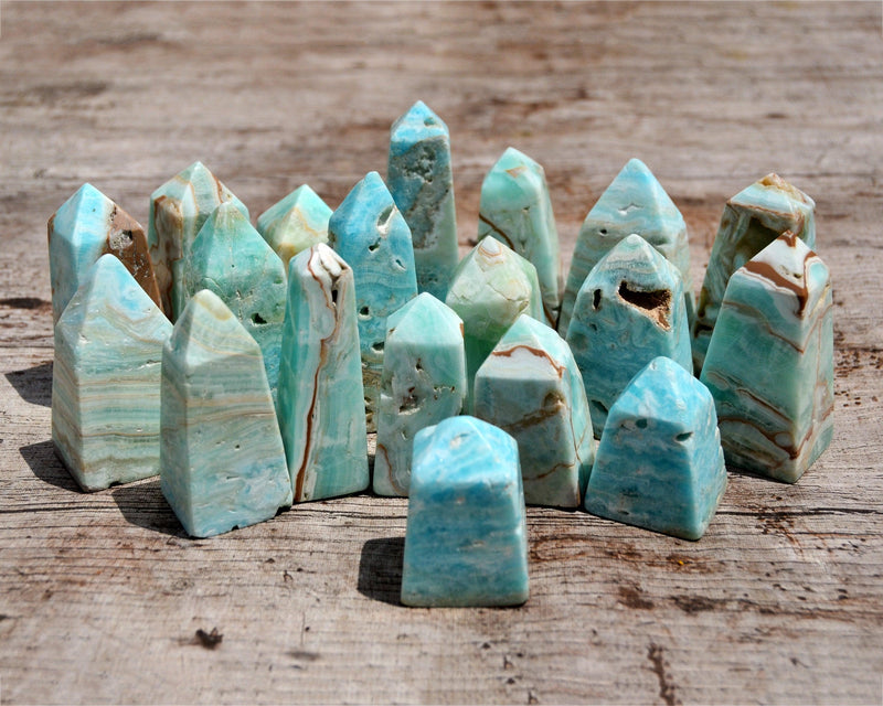 Several small blue green aragonite crystal obelisks on wood table